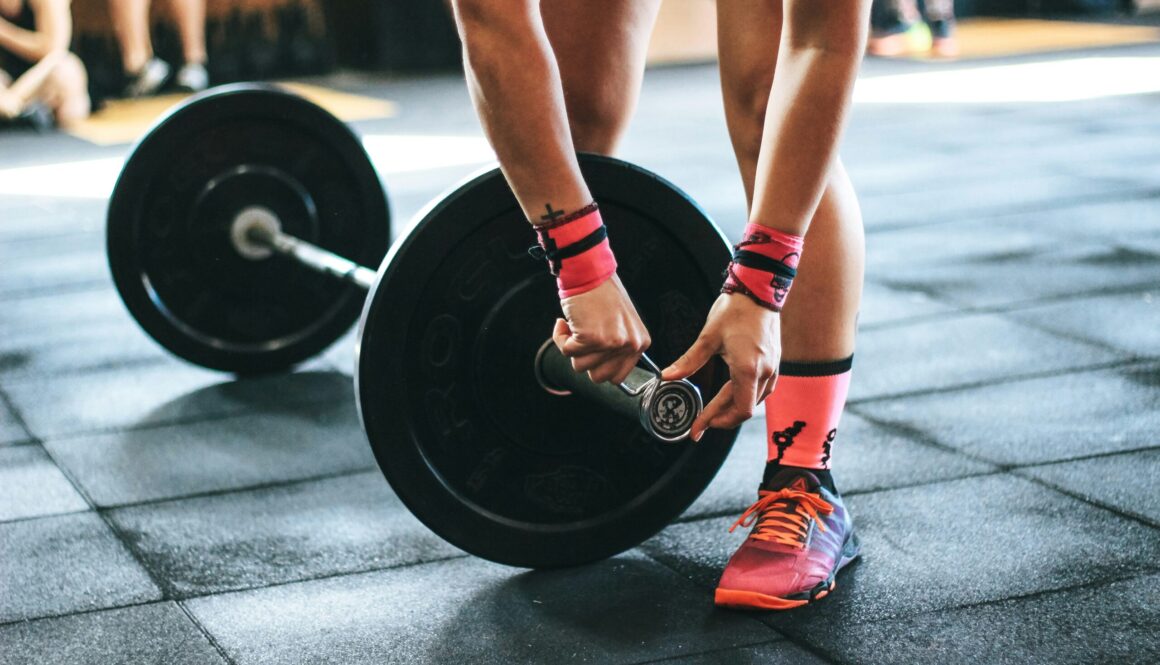 person locking gym plates on barbell