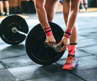 person locking gym plates on barbell